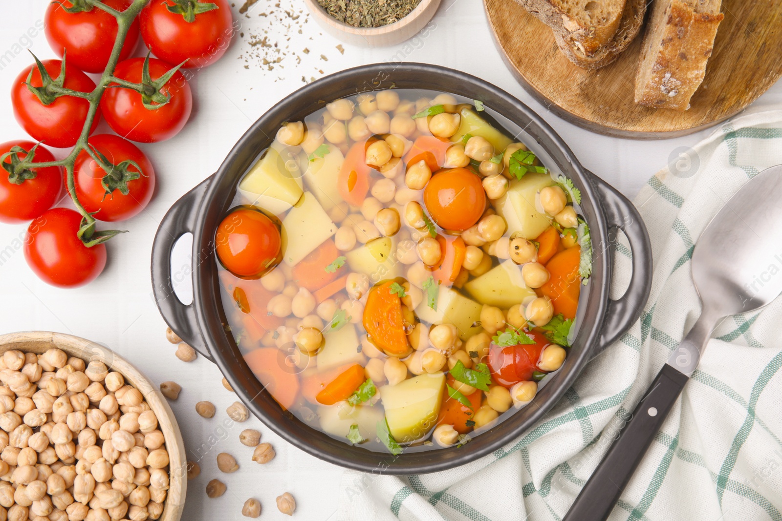 Photo of Flat lay composition of tasty chickpea soup served on white tiled table