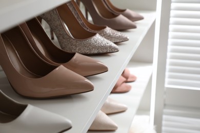 Different stylish women's shoes on shelf in dressing room, closeup