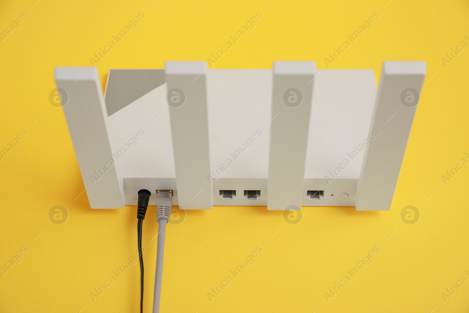 Photo of Modern Wi-Fi router on yellow background, above view