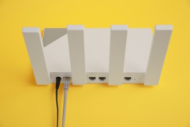 Modern Wi-Fi router on yellow background, above view