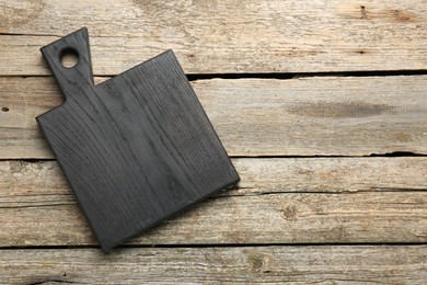 Black cutting board on old wooden table, top view. Space for text