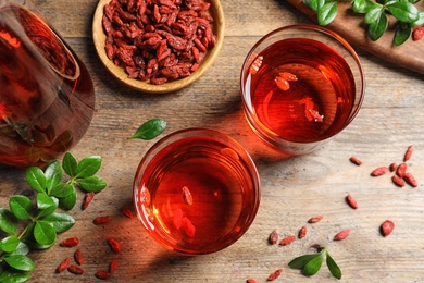 Photo of Flat lay composition with healthy goji juice on wooden table