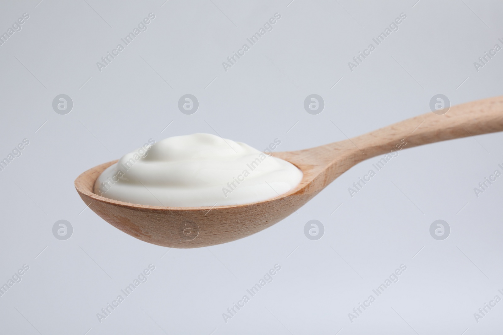 Photo of Delicious natural yogurt in spoon on light background