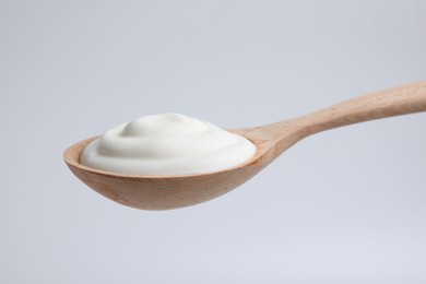 Delicious natural yogurt in spoon on light background