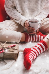 Image of Woman relaxing with cup of hot winter drink on knitted plaid, closeup. Cozy season