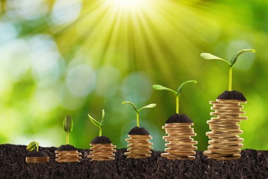 Stacked coins and green seedlings on ground outdoors, bokeh effect. Investment concept