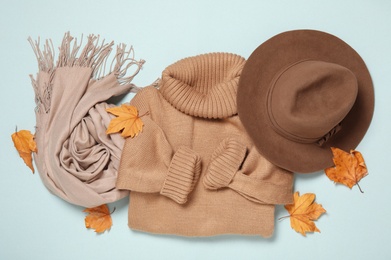 Photo of Flat lay composition with sweater and dry leaves on light blue background. Autumn season