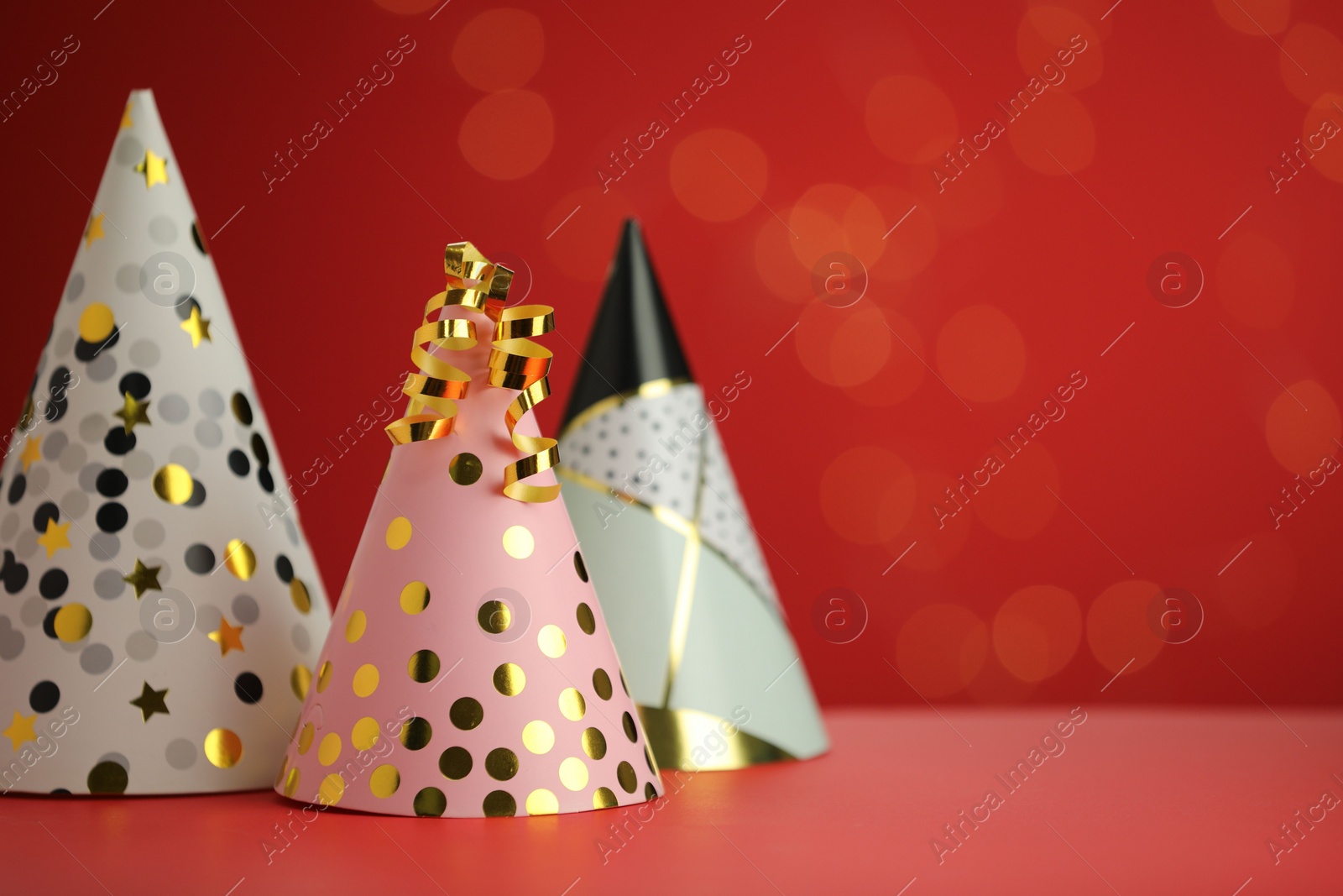 Photo of Beautiful party hats and serpentine streamers on red background, space for text