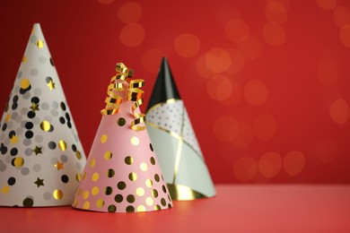 Photo of Beautiful party hats and serpentine streamers on red background, space for text