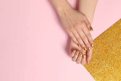 Photo of Woman showing manicured hands with golden nail polish on color background, top view. Space for text