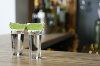 Photo of Mexican Tequila with salt and lime slices on bar counter. Space for text