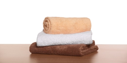 Photo of Soft colorful terry towels on wooden table against white background