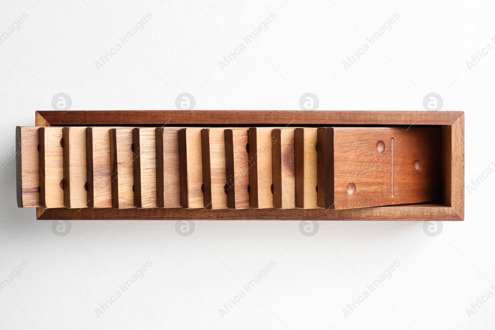 Photo of Set of wooden dominoes in box on white table, top view