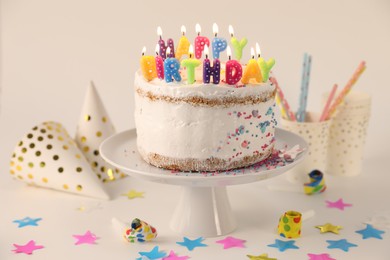 Tasty Birthday cake with burning candles and party decor on white table