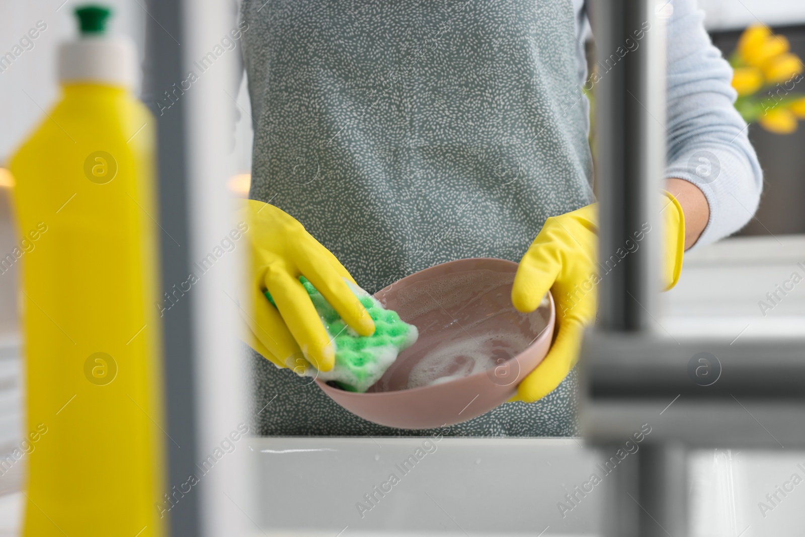 Photo of Woman washing plate above sink in modern kitchen, closeup