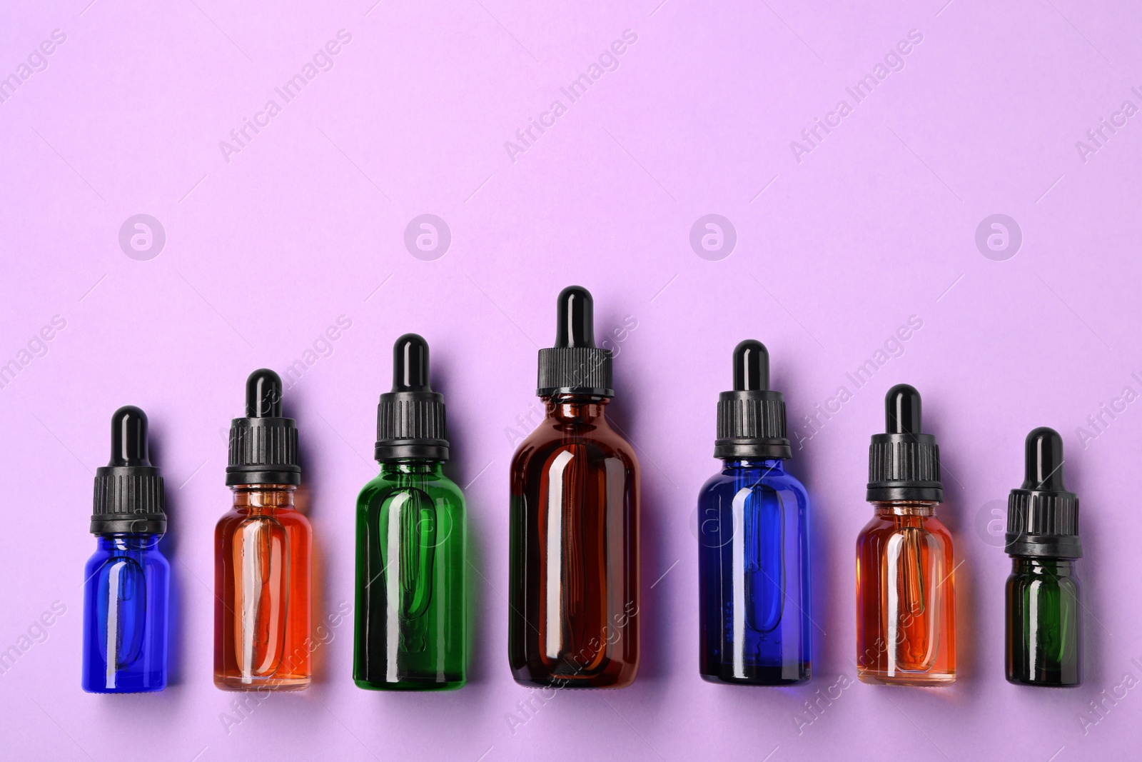 Photo of Bottles of essential oils on color background, flat lay. Cosmetic products