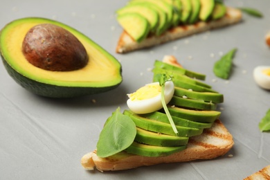 Tasty avocado toasts on light grey table