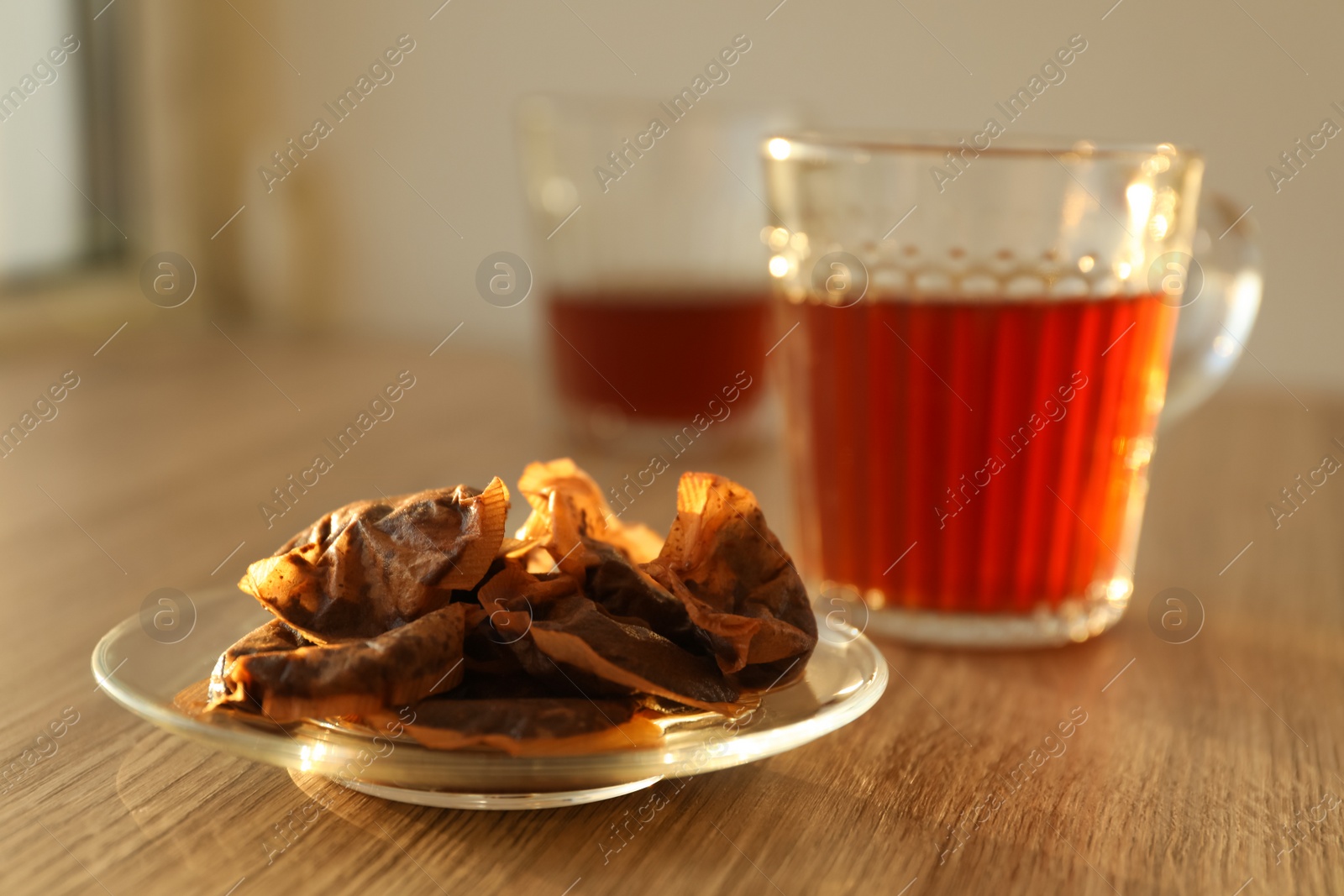 Photo of Glass saucer with used tea bags on wooden table