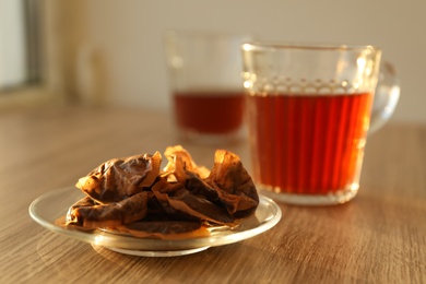 Photo of Glass saucer with used tea bags on wooden table