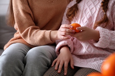 Photo of Girls with fresh tangerine sitting on sofa indoors, closeup