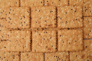 Cereal crackers with flax and sesame seeds as background, top view