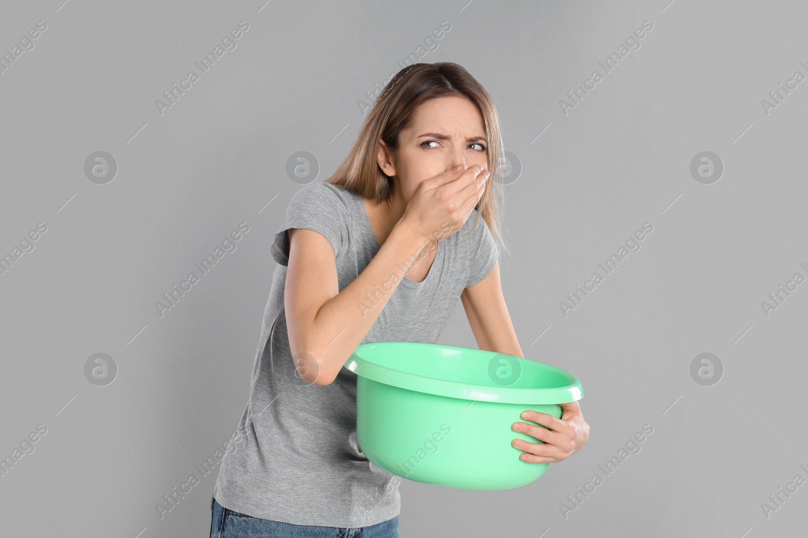 Photo of Woman with basin suffering from nausea on grey background. Food poisoning