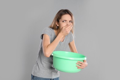 Photo of Woman with basin suffering from nausea on grey background. Food poisoning