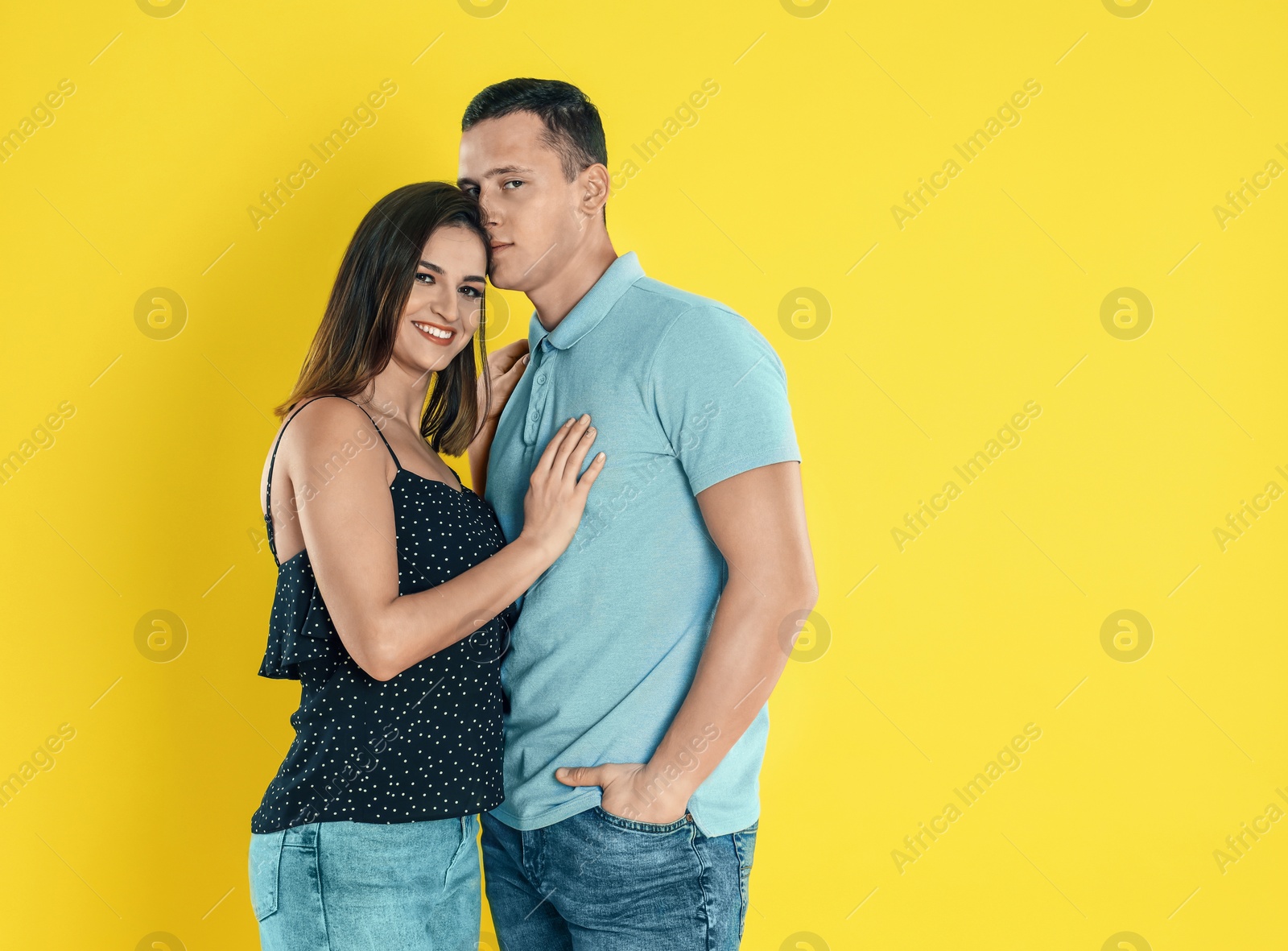 Photo of Happy young couple hugging on yellow background. Space for text