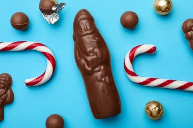 Photo of Flat lay composition with chocolate Santa Claus candies and sweets on light blue background