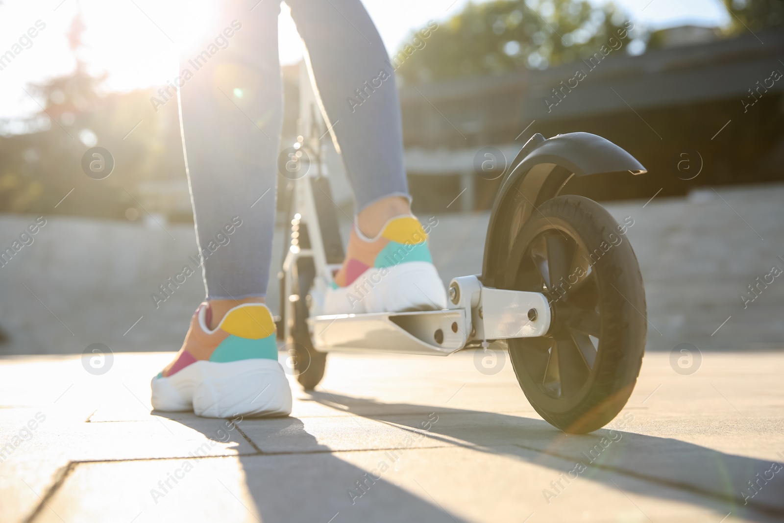 Photo of Woman riding electric kick scooter outdoors, closeup