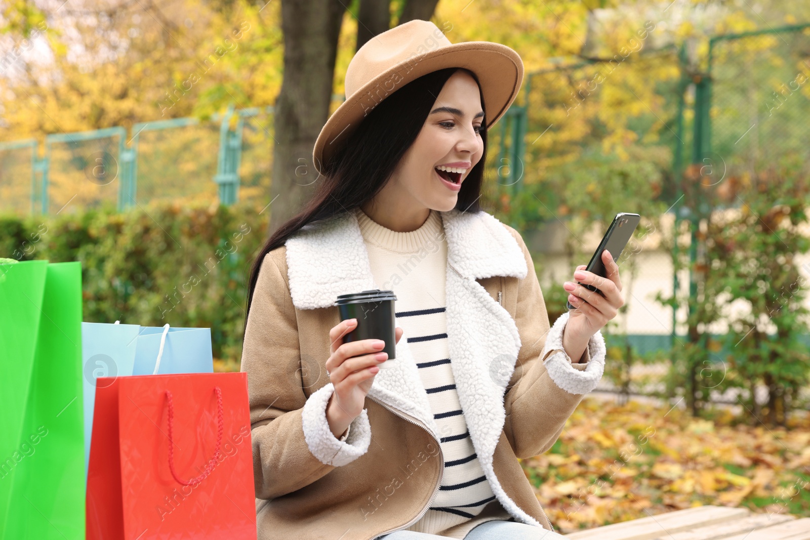 Photo of Special Promotion. Emotional young woman with smartphone and cup of drink in park