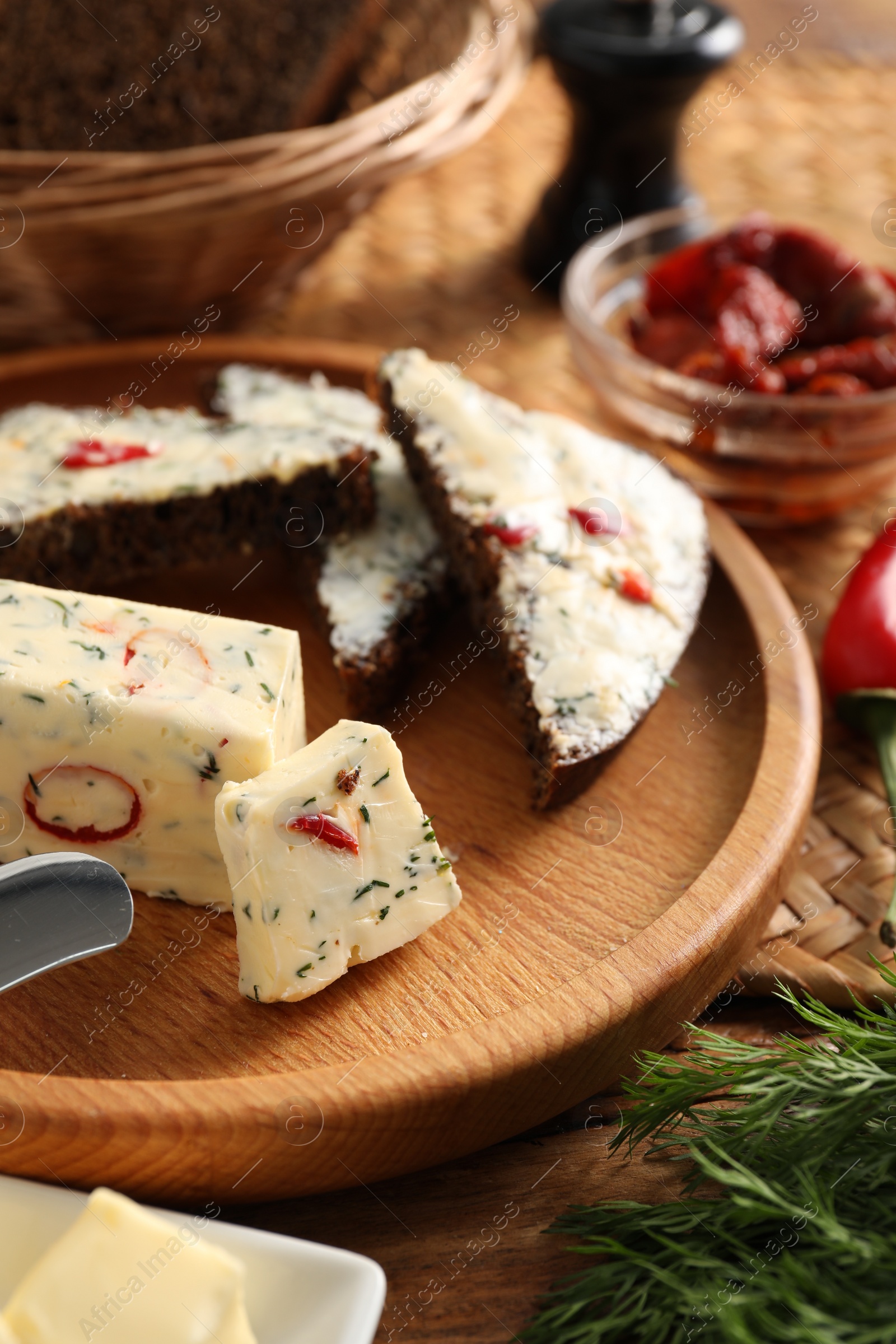 Photo of Tasty butter with dill, chili pepper and rye bread on table