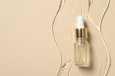 Photo of Bottlecosmetic serum on beige background, top view. Space for text