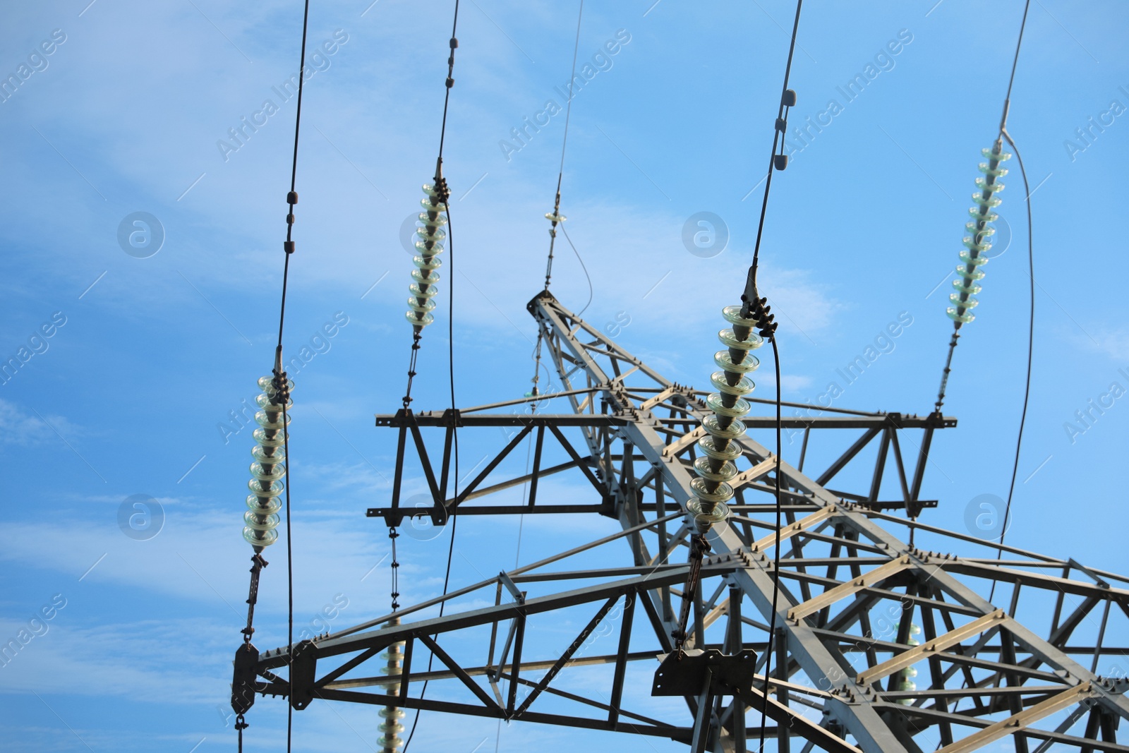 Photo of High voltage tower against blue sky on sunny day, low angle view