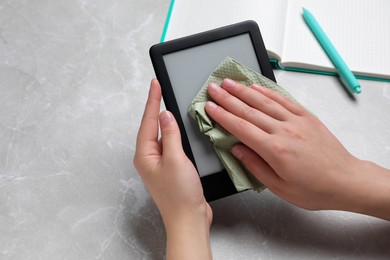 Photo of Woman wiping smartphone with paper at gray marble table, closeup