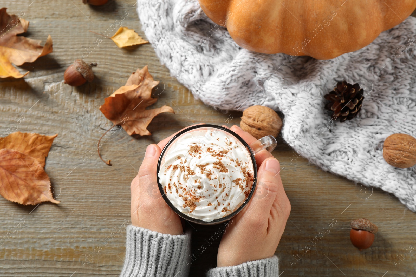 Photo of Woman with cup of pumpkin spice latte at wooden table, top view