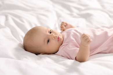 Photo of Cute little baby lying on white sheets