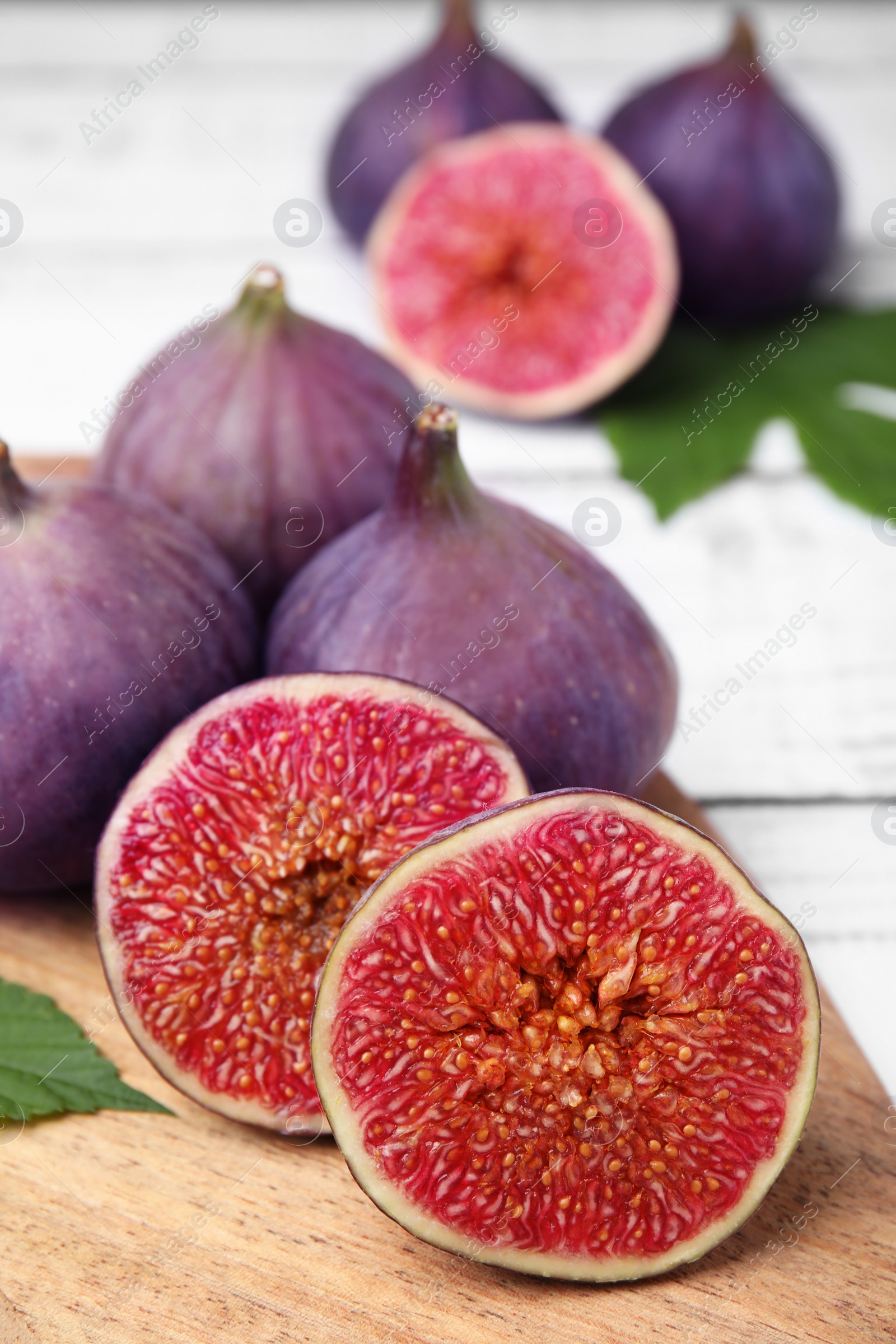 Photo of Fresh ripe figs on white wooden table, closeup