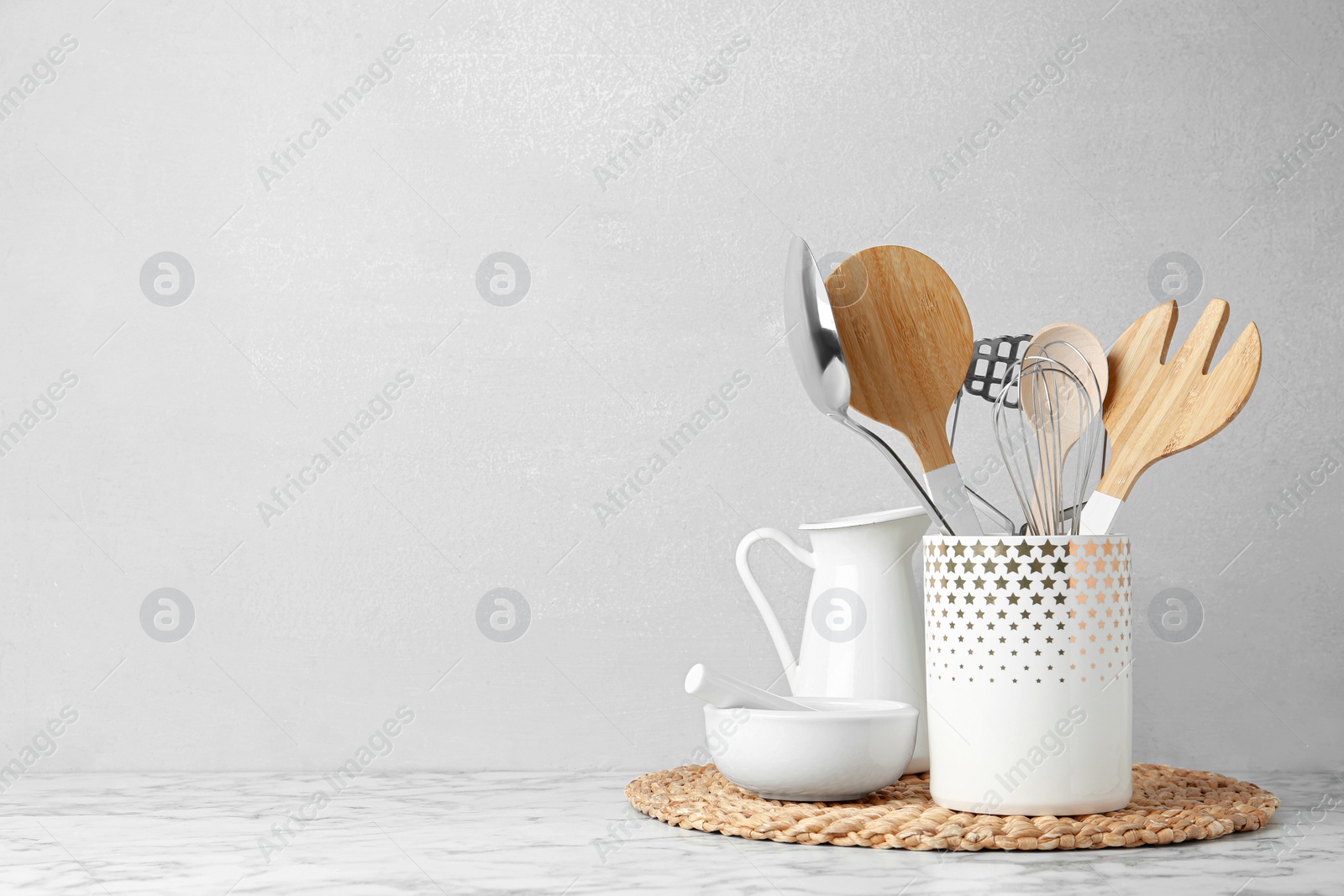 Photo of Different kitchen utensils on table against light background. Space for text