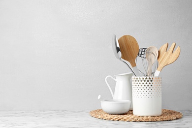 Different kitchen utensils on table against light background. Space for text