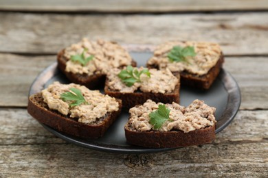 Tasty sandwiches with cod liver and parsley on wooden table