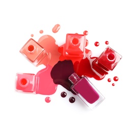 Photo of Spilled different nail polishes with bottles on white background, top view