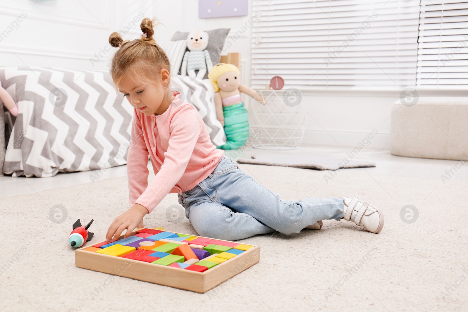 Photo of Cute little girl playing with colorful building blocks at home