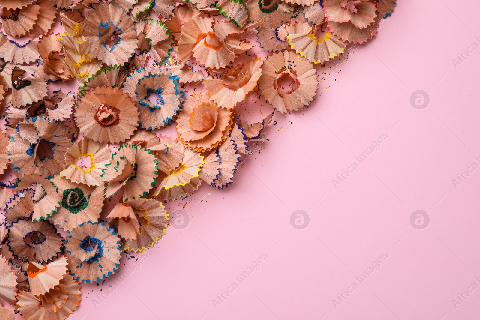 Photo of Wooden pencil shavings and colorful crumbs on pink background, flat lay. Space for text