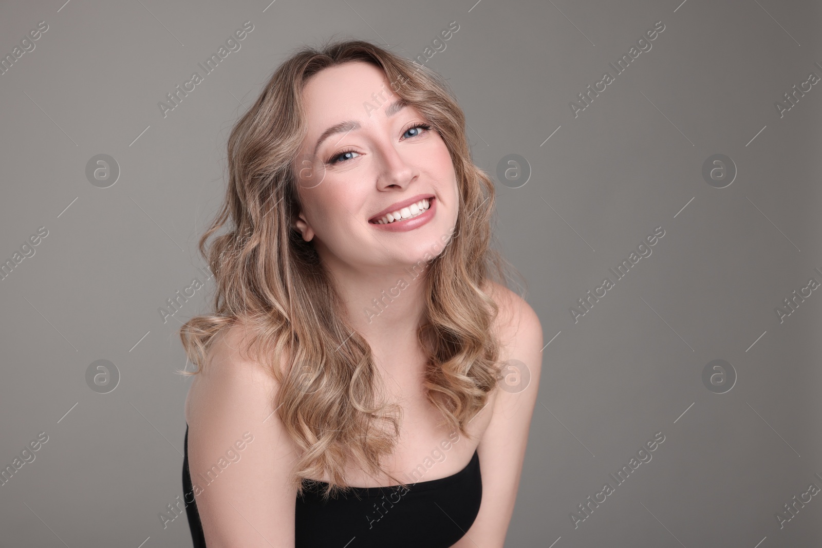 Photo of Portrait of smiling woman with curly hair on grey background. Space for text