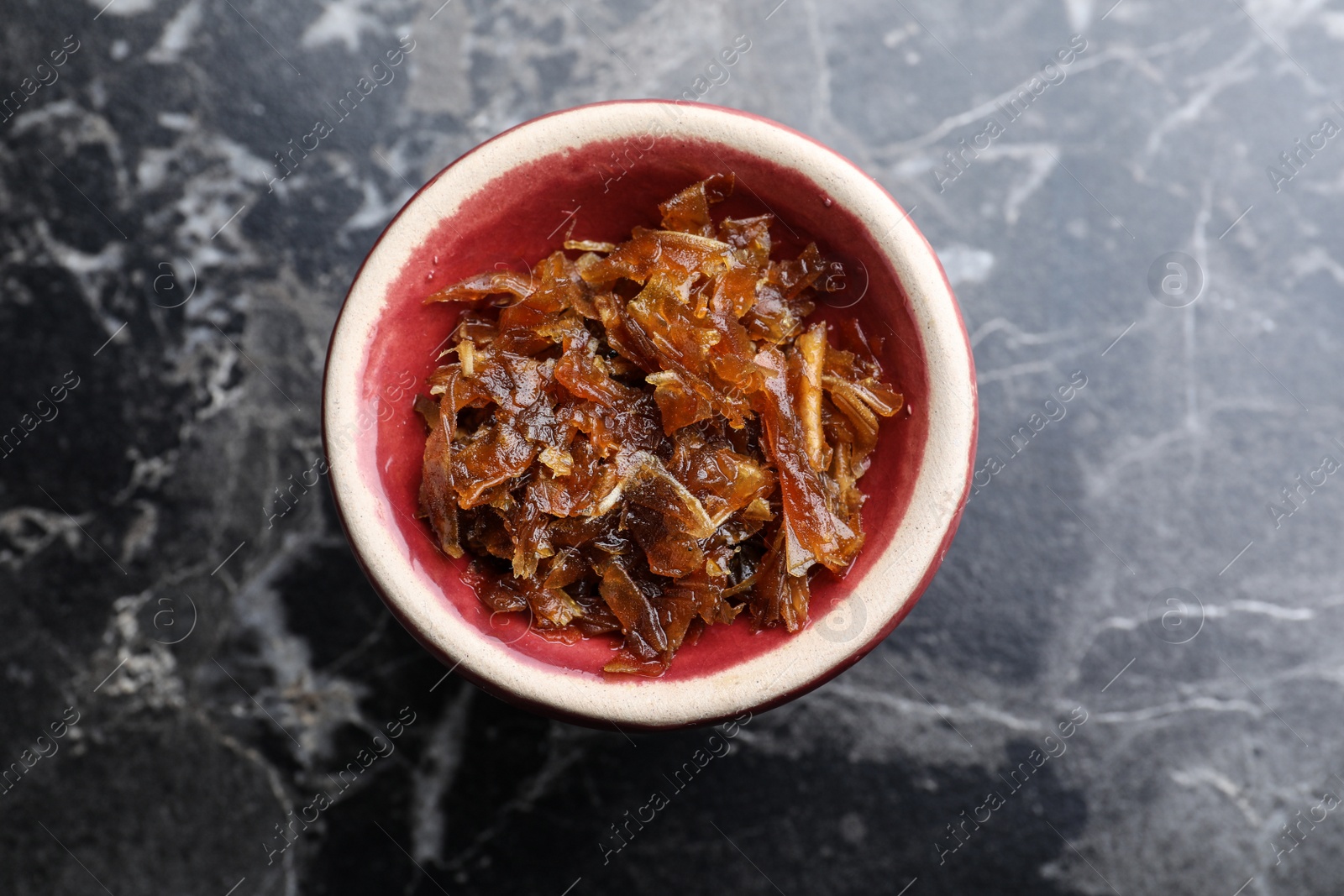 Photo of Modern hookah bowl with tobacco on black marble table, top view