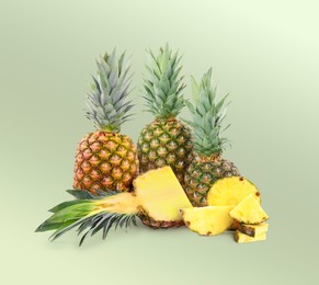 Image of Cut and whole pineapples on pale green background