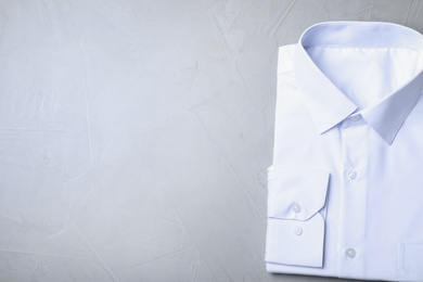 Stylish white shirt on grey background, top view with space for text. Dry-cleaning service