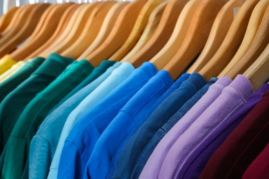 Photo of Hangers with bright clothes as background, closeup