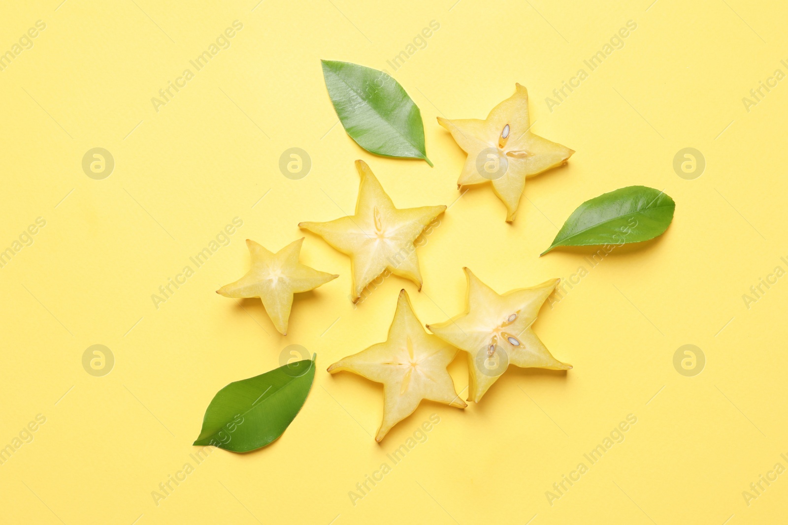 Photo of Delicious carambola slices on yellow background, flat lay